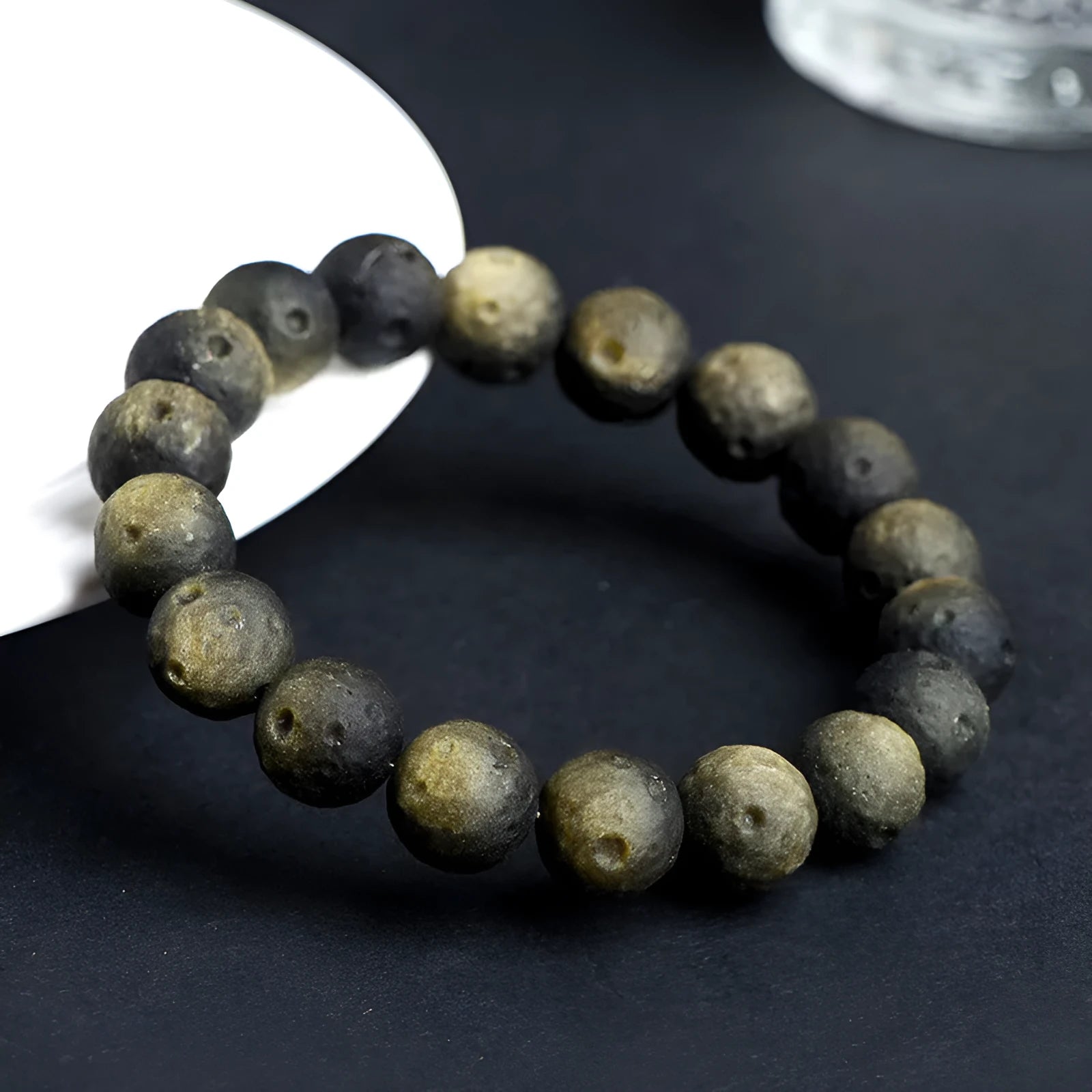 Natural obsidian crater ball bracelet showing textured beads in silver stone or golden obsidian colour on a wrist.