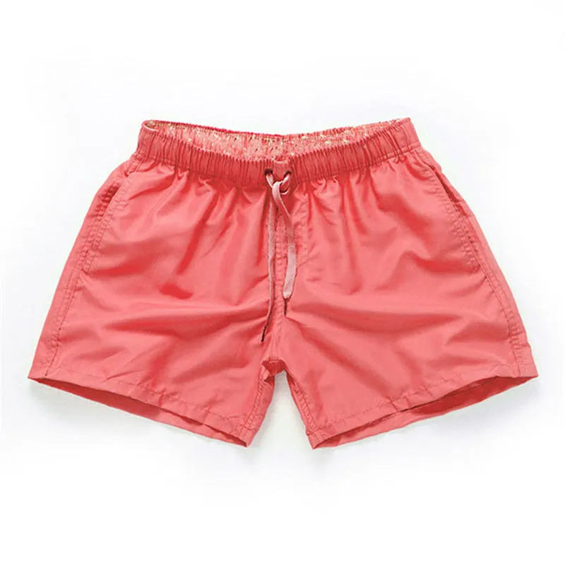 Men's straight-leg polyester beach shorts on a hanger, showing the classic fit and available in multiple solid colours.