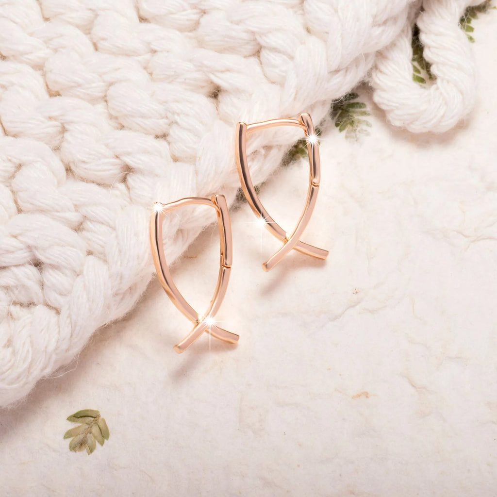 Single pair of rose gold cross shaped earrings made from copper with light luxury design