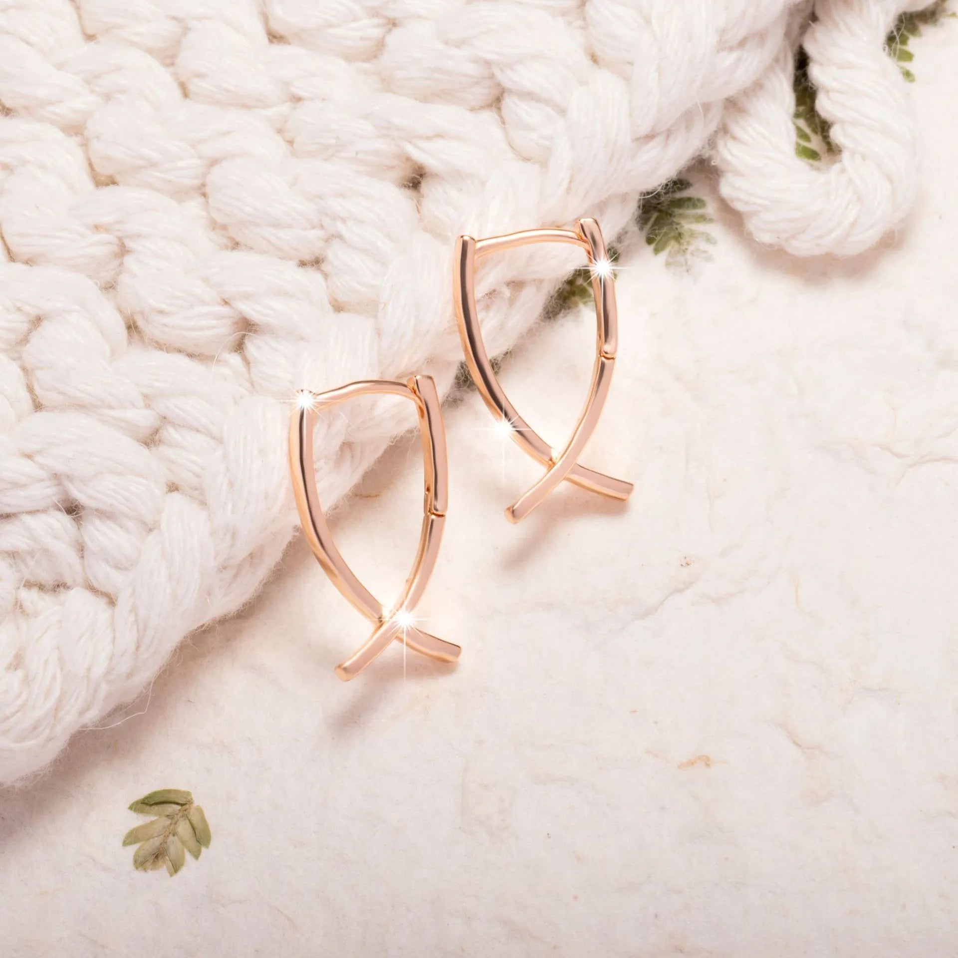Single pair of rose gold cross shaped earrings made from copper with light luxury design