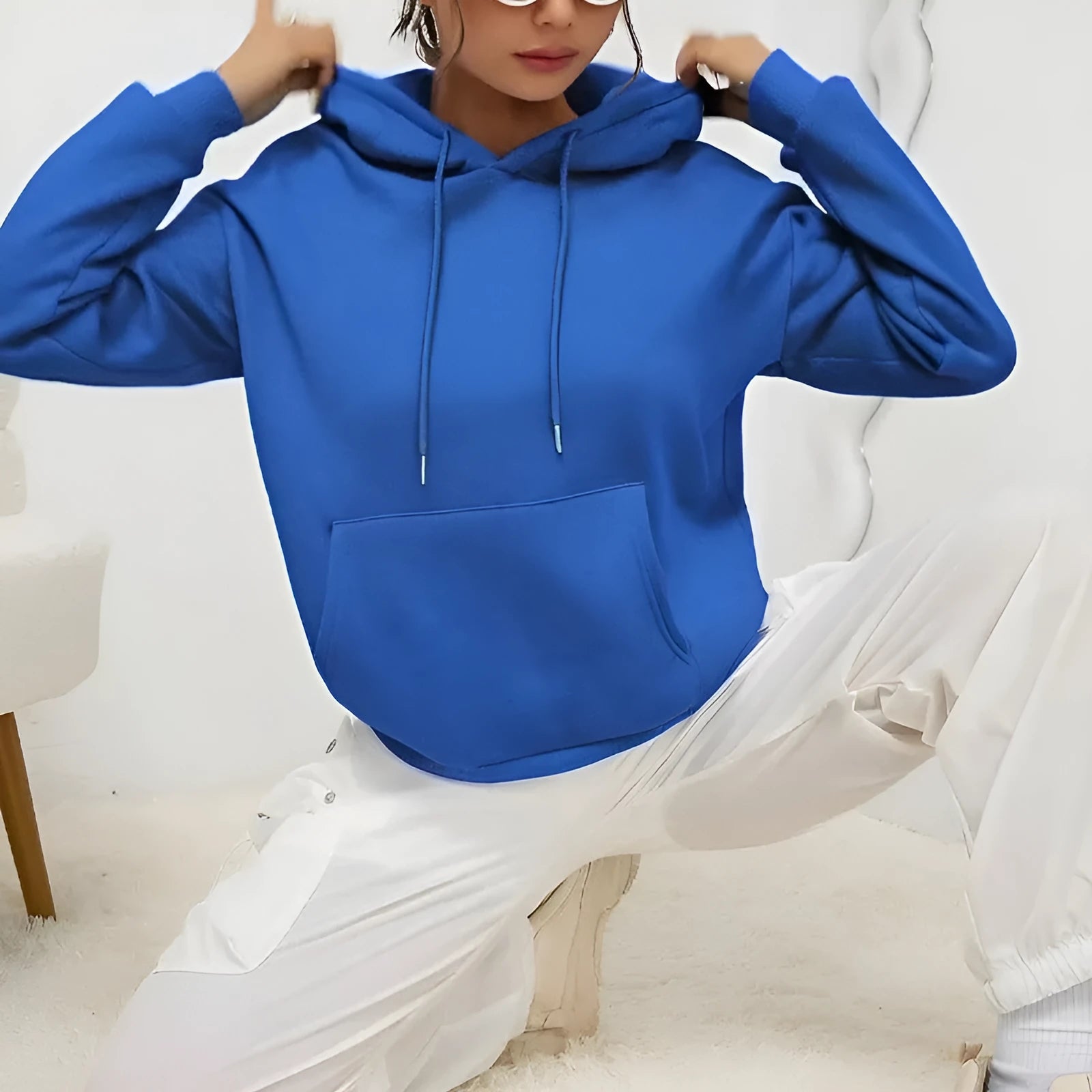 Woman wearing a loose grey drawstring hoodie with front kangaroo pocket, long sleeves.