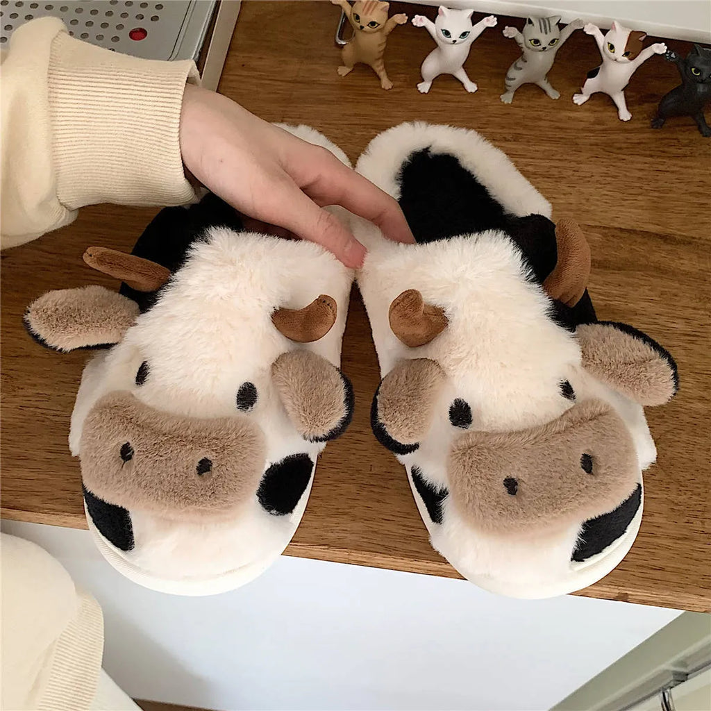 White and coffee coloured cow animal slippers for women with a plush exterior and non-slip sole.