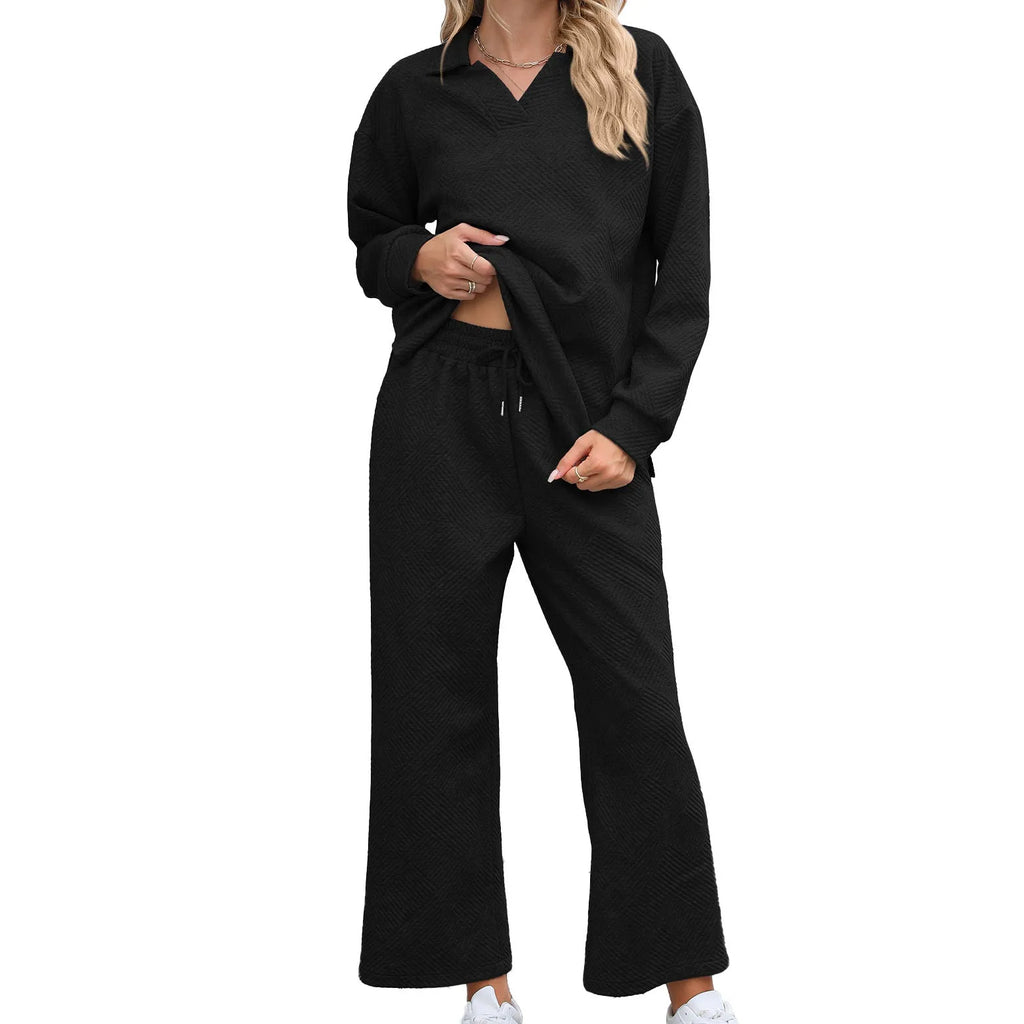 Women's black knitted jacquard two-piece suit with long sleeve top and elastic waist cropped trousers on a hanger.