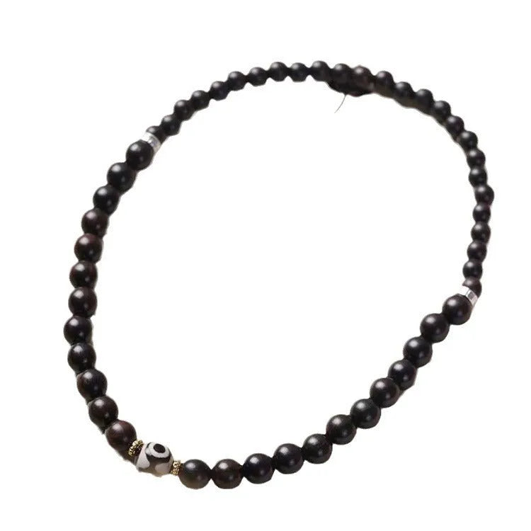 Ebony beaded bracelet with two-circle Tibetan-inspired design on wrist