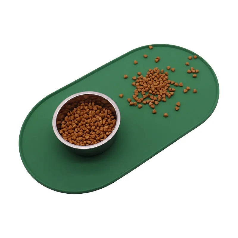 Green silicone placemat for cat bowls on a wooden floor.
