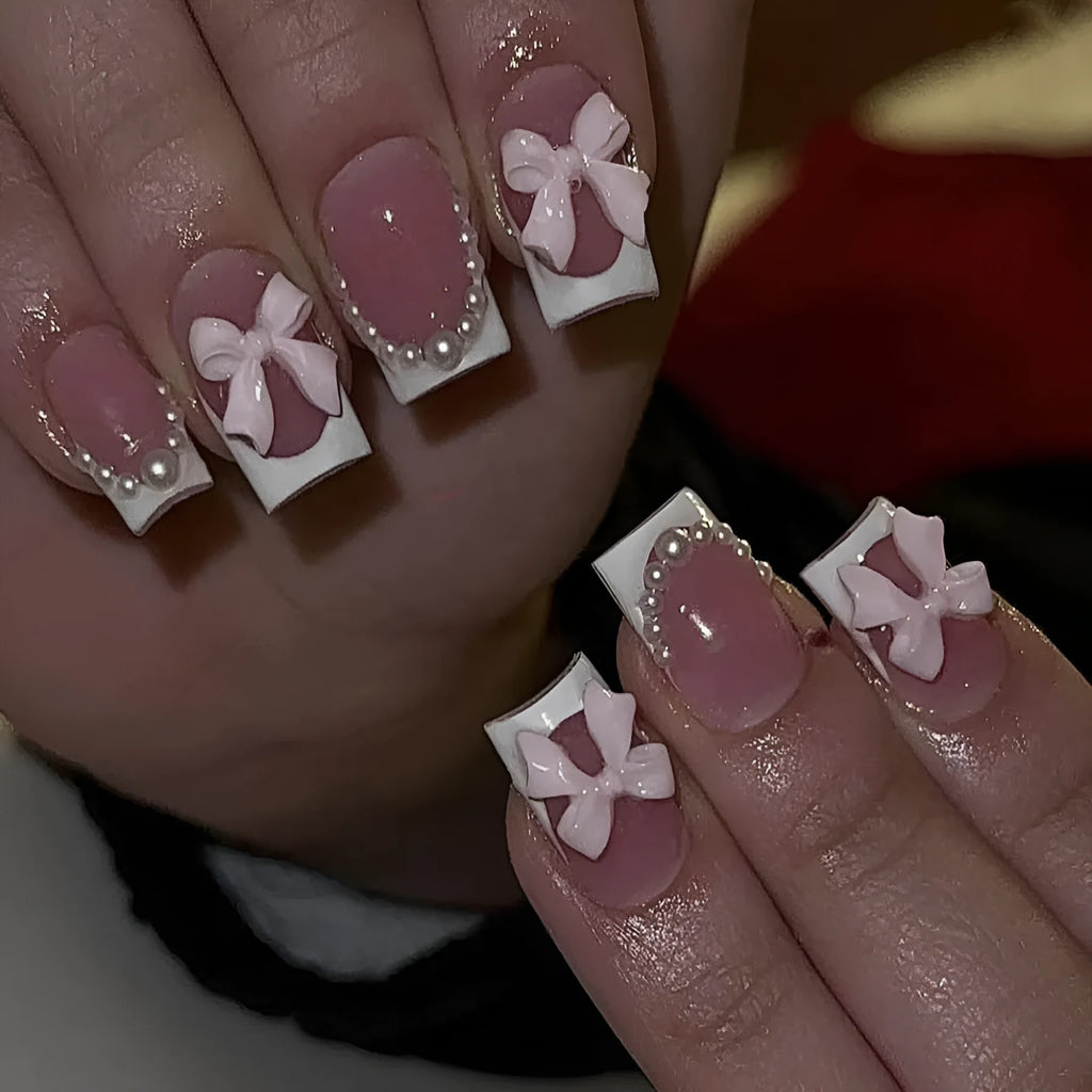 Short white French false nails with bow and tulip designs on a European square shape.