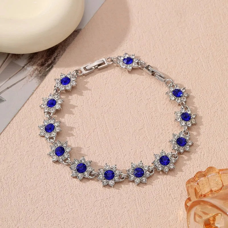 Electroplated zinc alloy bracelet with flower-shaped coloured gems in gold or silver tone.