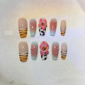 Close-up of zebra pattern artificial nails with embossed lily flower and leopard print designs, shown in long wear-resistant style.