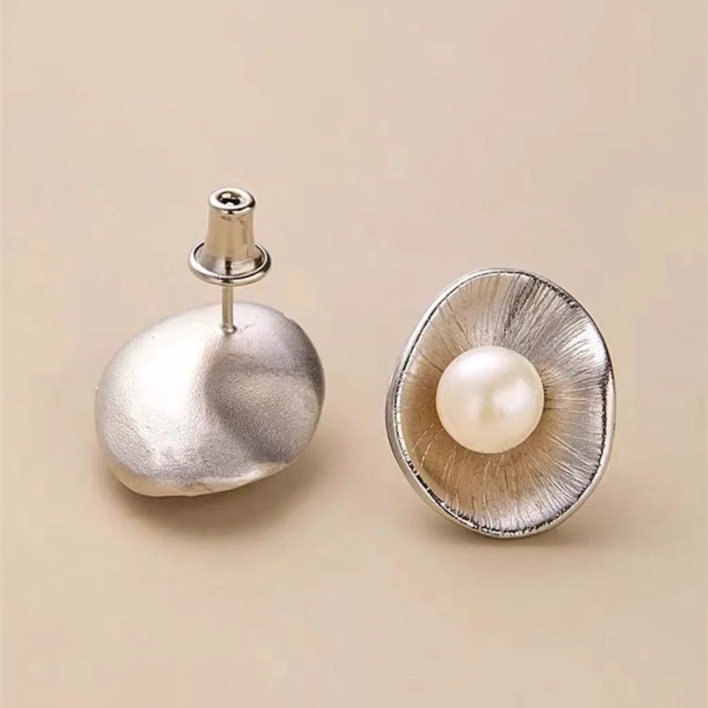 A pair of silver geometric pearl ear studs with gold electroplated finish on needle posts.