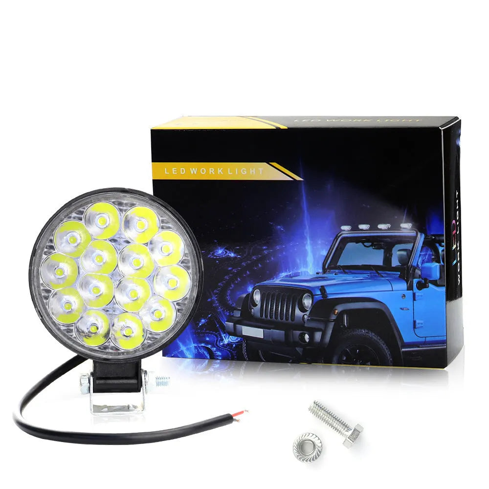 White mini round LED work light with aluminium housing, mounted as an auxiliary car or truck light.