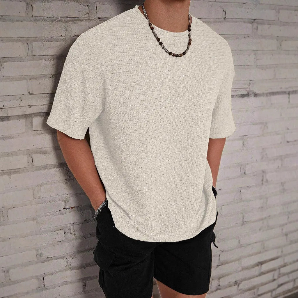 Man wearing a slim fit black round neck T-shirt with a loose hollow knit texture.