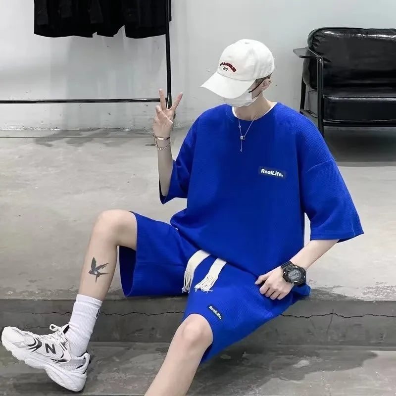 Man wearing a grey waffle-textured cotton blend short sleeve top and matching shorts leisure set.