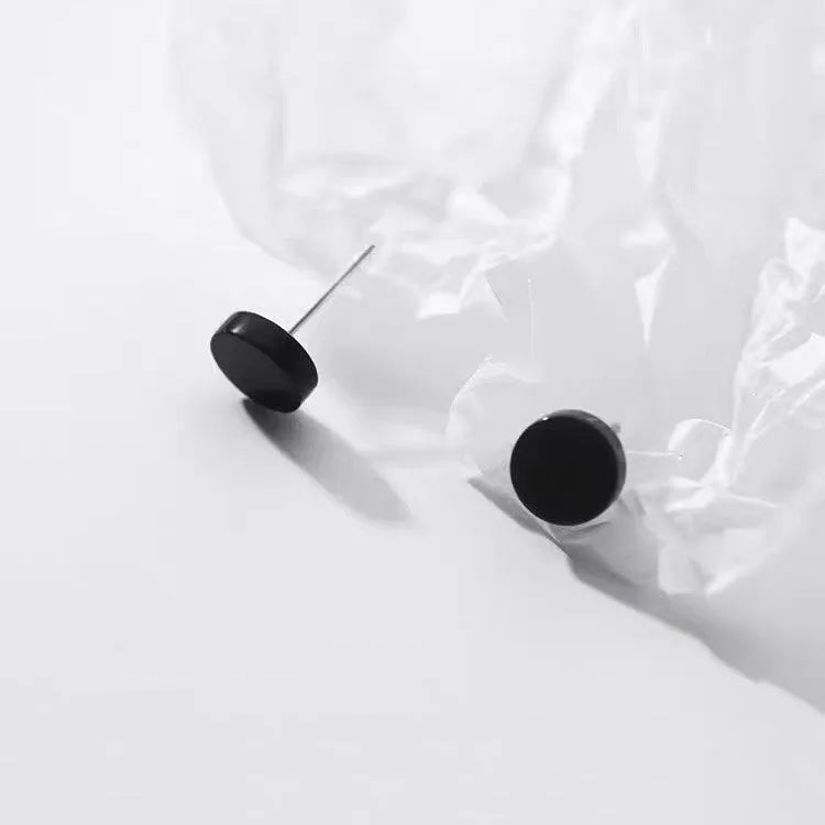 A pair of small, round, flat sterling silver stud earrings for cartilage piercing on a plain background.