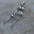 Pair of long geometric pendant earrings in antique silver with rhinestone detail on a white background.