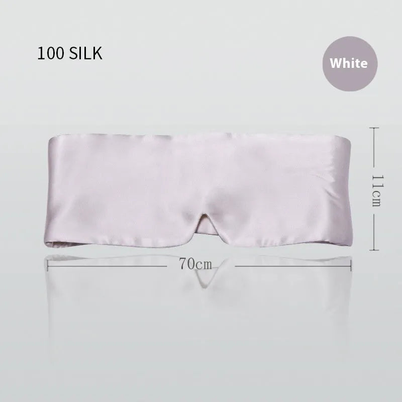 Mulberry silk sleep mask in black shown on a bed.