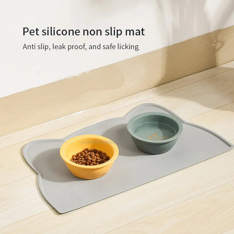 Blue waterproof silicone pet feeding mat for dog or cat bowls on a wooden floor.