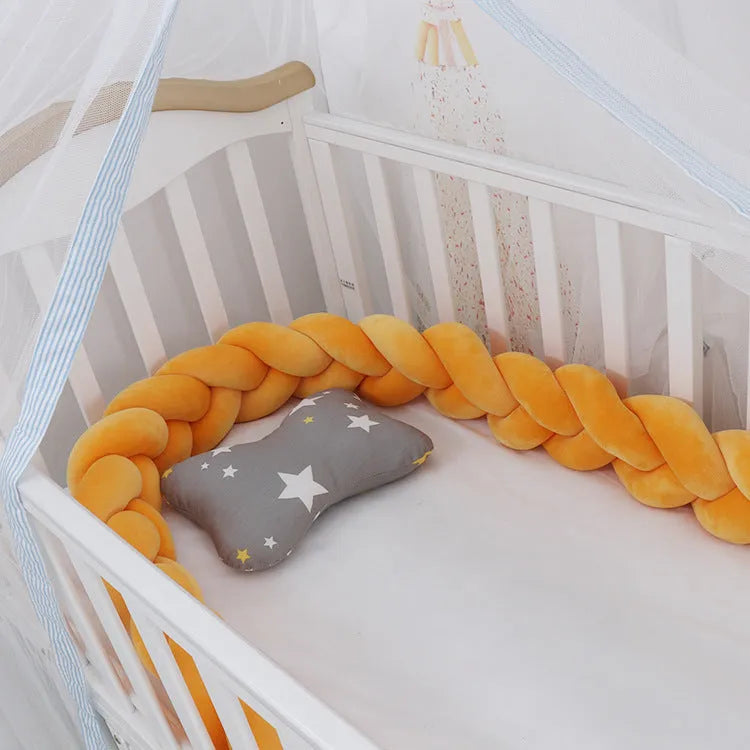 Flexible braided cot bumper made of soft spandex velvet, shown in a light grey colour wrapped around a crib.