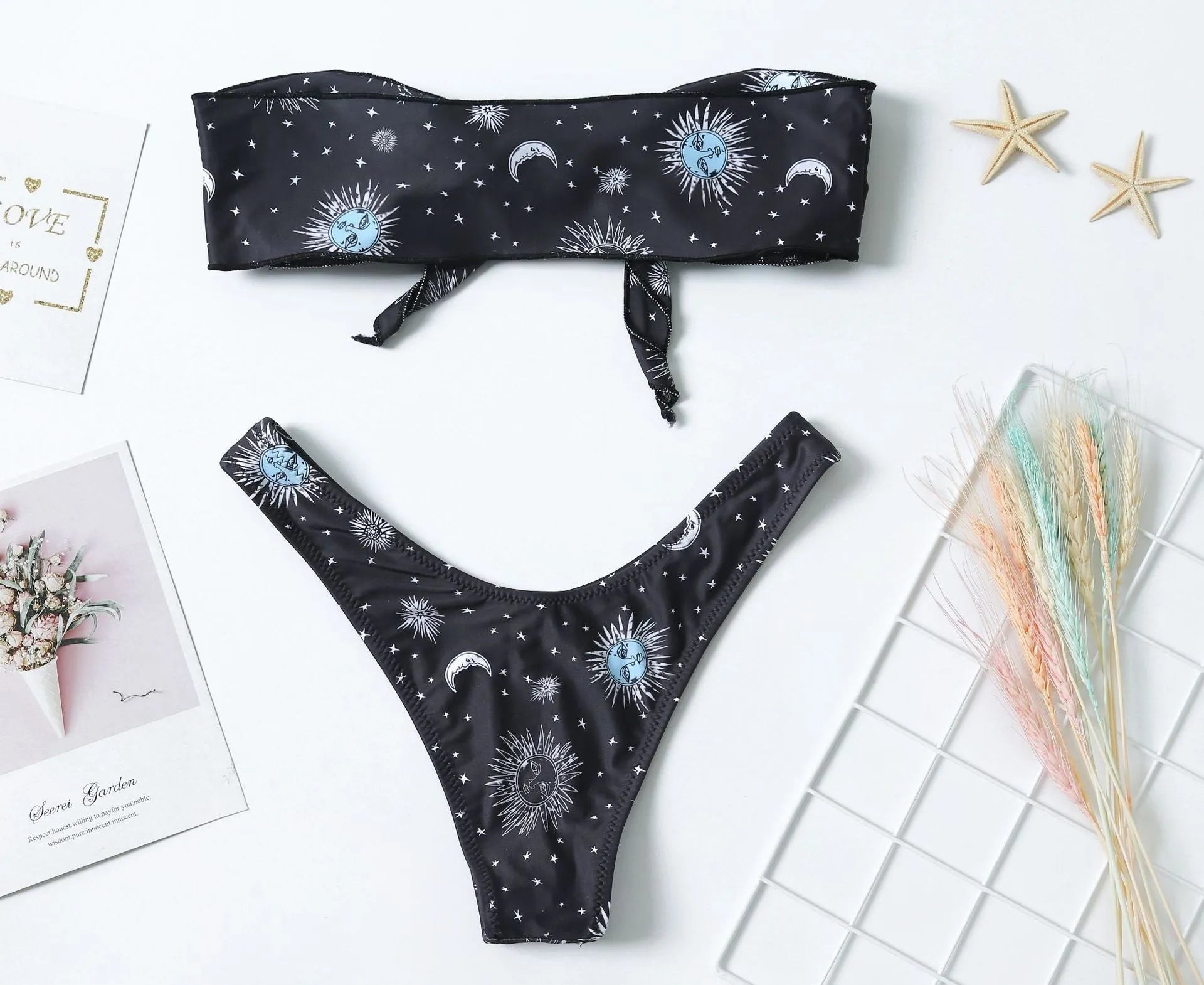 Black one-piece swimsuit with a bikini print pattern, featuring a split tube top and backless design.