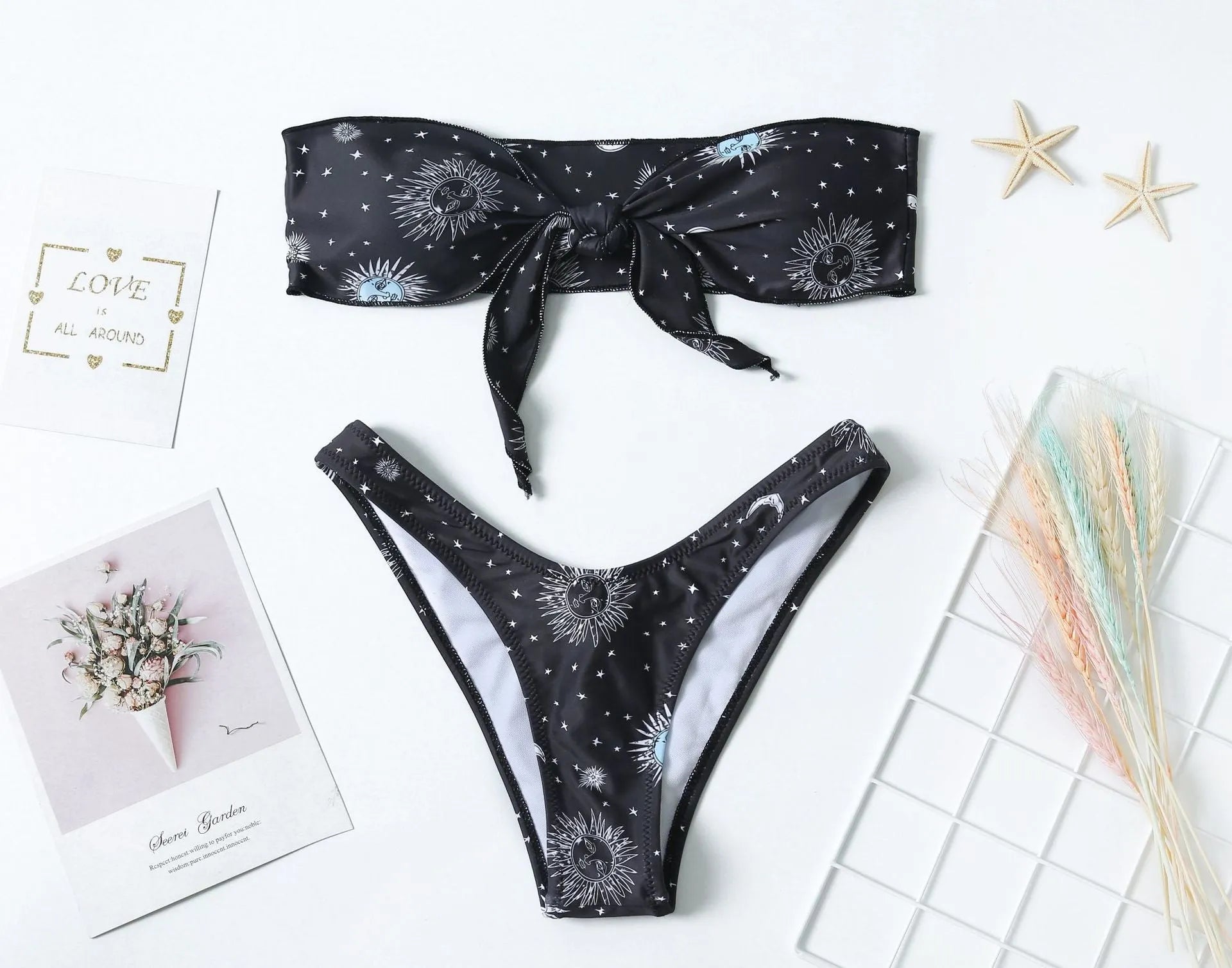 Black one-piece swimsuit with a bikini print pattern, featuring a split tube top and backless design.