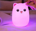 Cartoon silicone clap lamp in blue with warm white light mode on a wooden bedside table