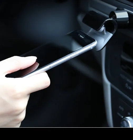 Black gravity car phone holder with adhesive mount, showing 360-degree rotation mechanism.