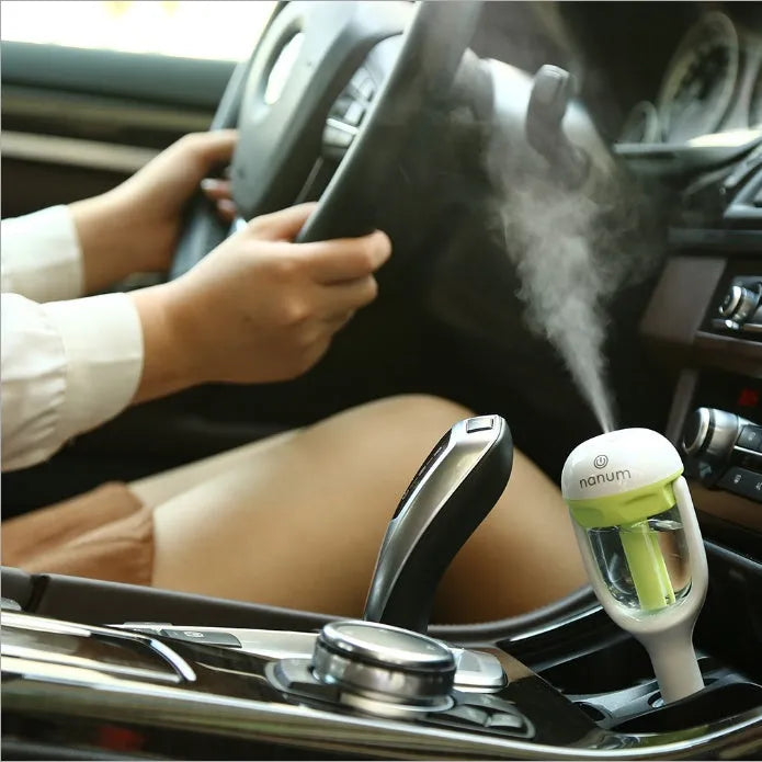 Compact blue car humidifier with rotation nozzle and essential oil diffusion capability on car dashboard