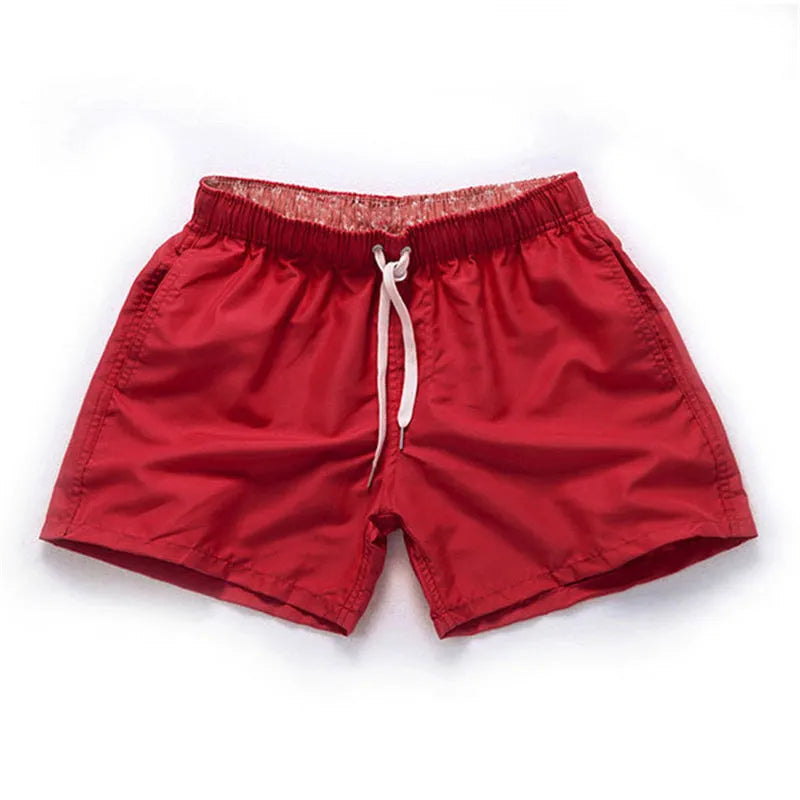 Men's straight-leg polyester beach shorts on a hanger, showing the classic fit and available in multiple solid colours.
