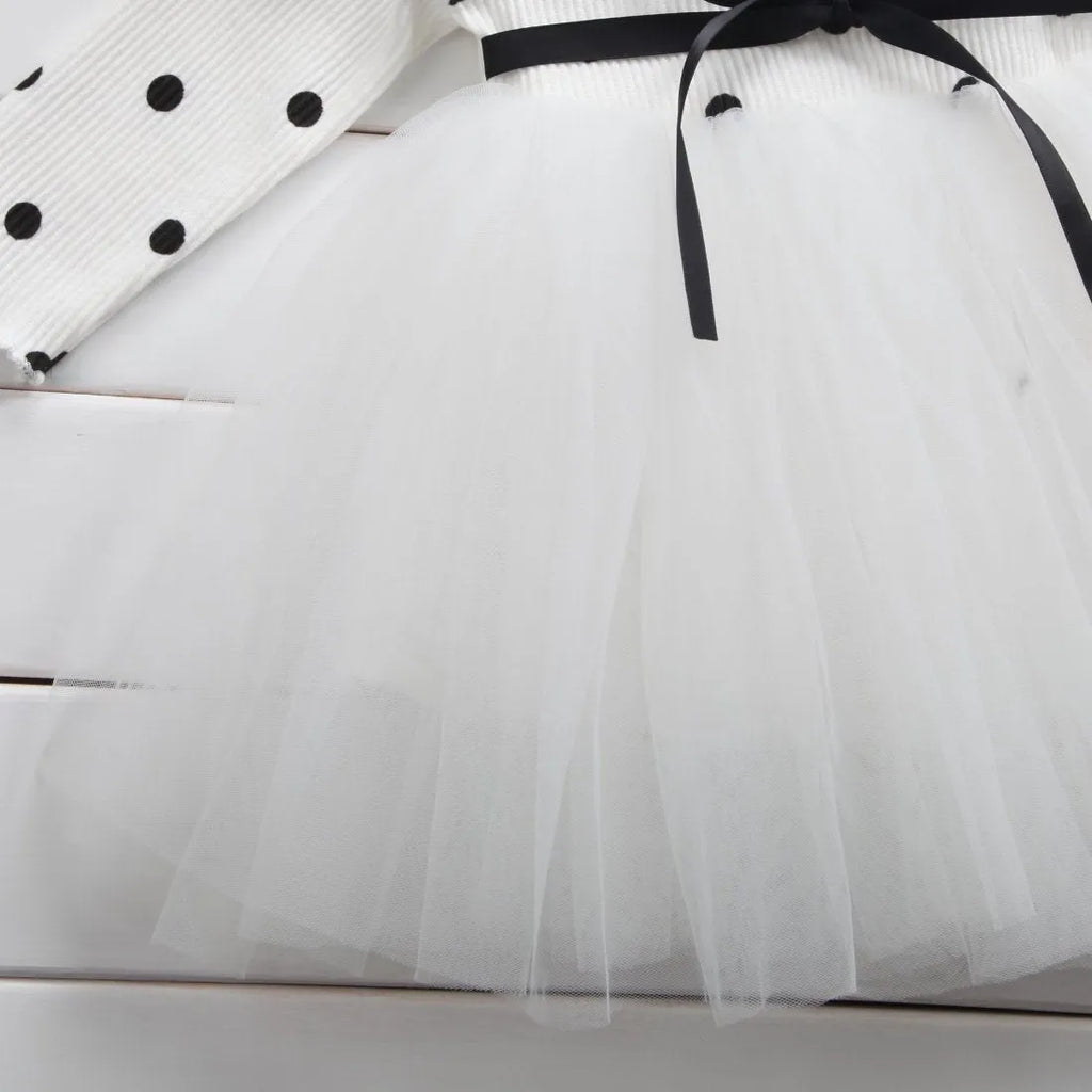 Baby girl in a long sleeve pink tutu dress with lace detailing on the sleeves.