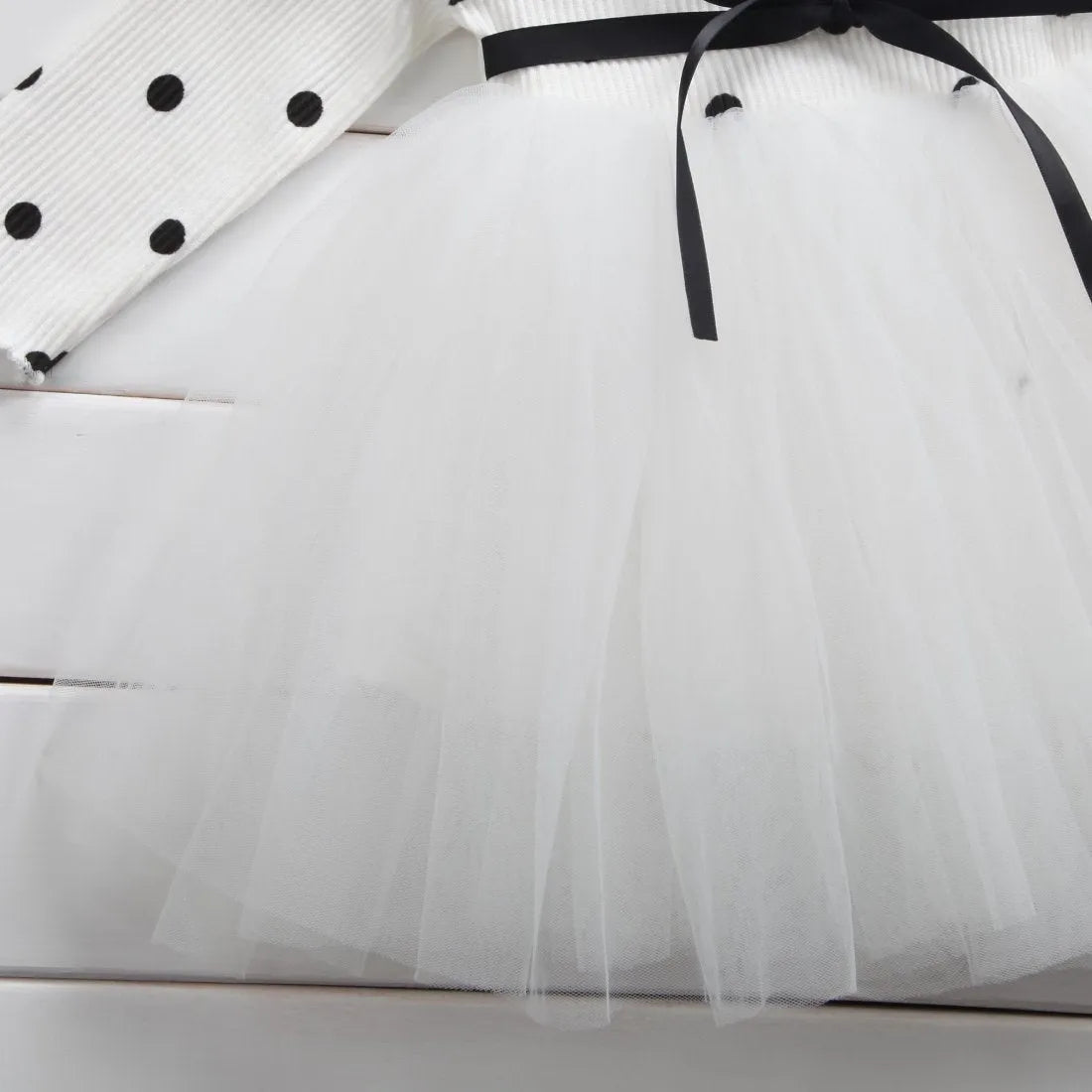 Baby girl in a long sleeve pink tutu dress with lace detailing on the sleeves.