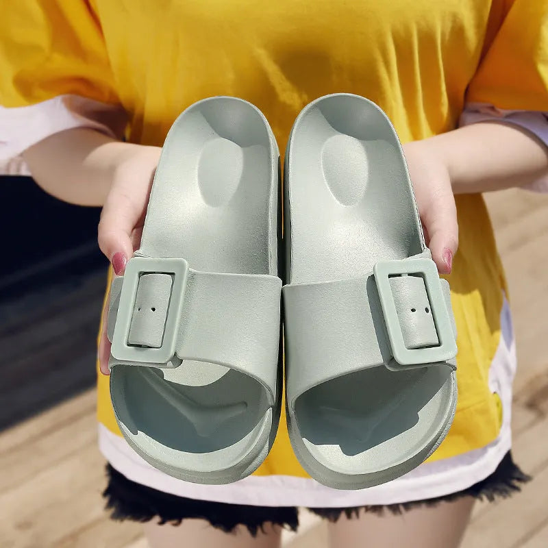 Women's grey blue EVA buckle slippers on a light background.