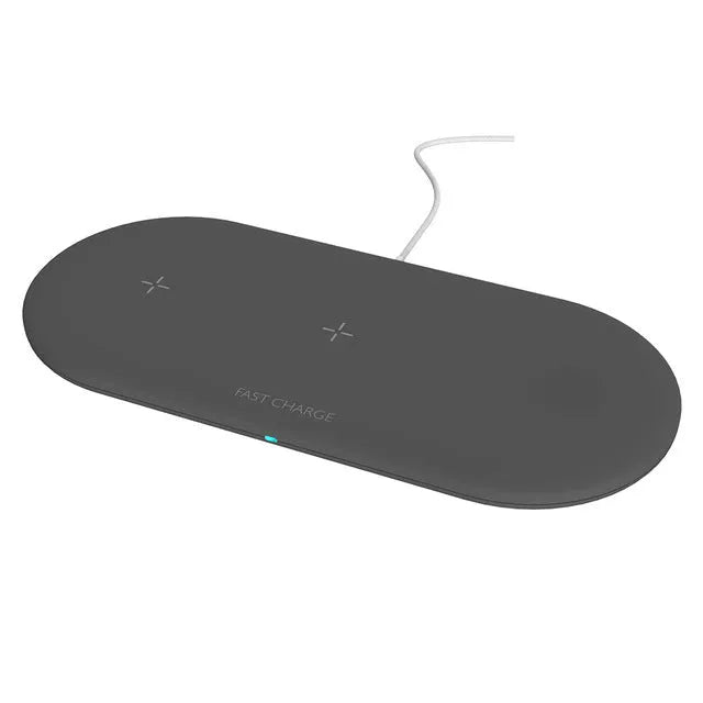 White three-in-one wireless charging stand holding an iPhone, Apple Watch, and AirPods on a wooden desk.