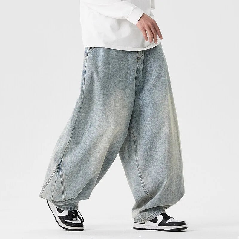 Men's plus-size baggy blue jeans with a wide leg and straight hem on a casual background.