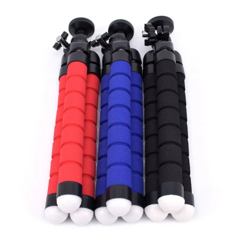 Black flexible octopus leg tripod standing on a table next to a smartphone
