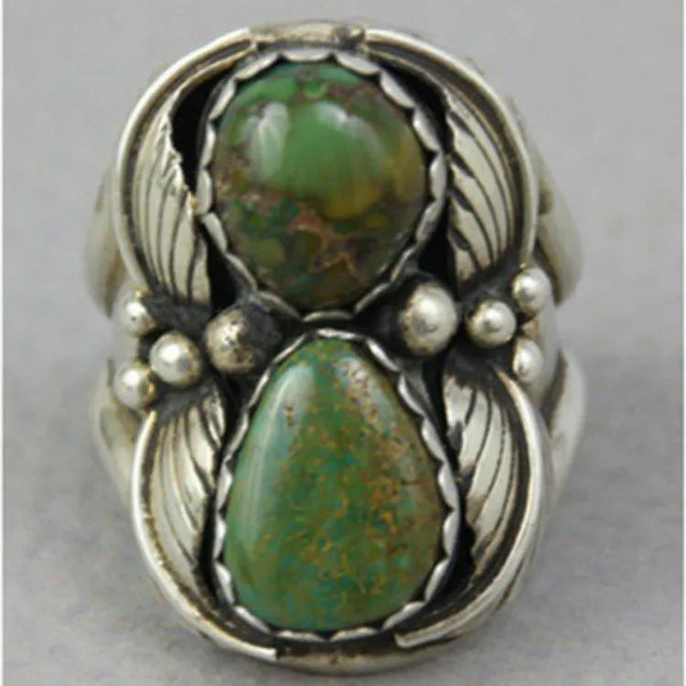 Close-up of a geometric alloy ring with a retro turquoise inlaid centre on a model's hand.