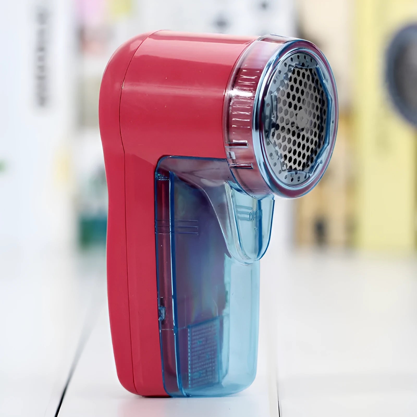 Compact blue portable electric lint remover for clothing on a grey sweater.