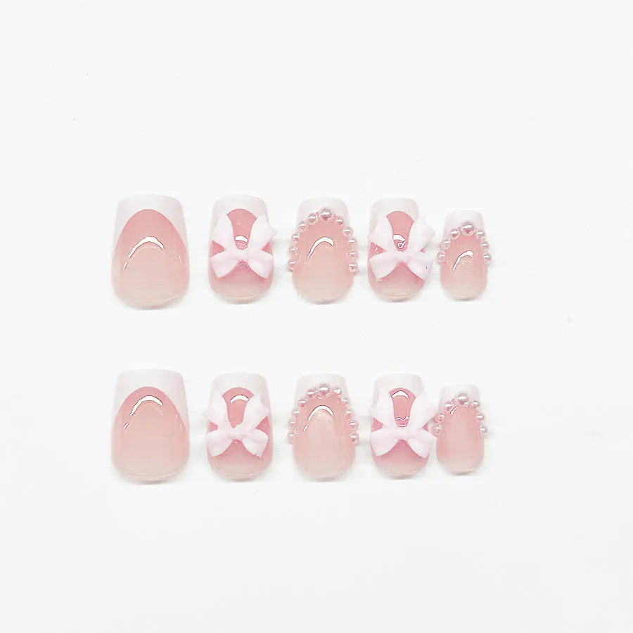 Short white French false nails with bow and tulip designs on a European square shape.