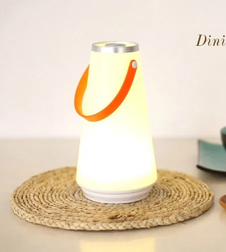 White rechargeable LED bedside table lamp with USB cable on a wooden surface.