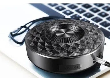 Compact black portable Bluetooth speaker on a table, showing its small size and design.