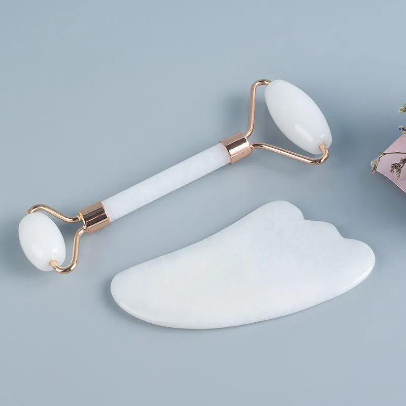 White jade double-headed facial roller and gua sha scraping board set on a neutral background.
