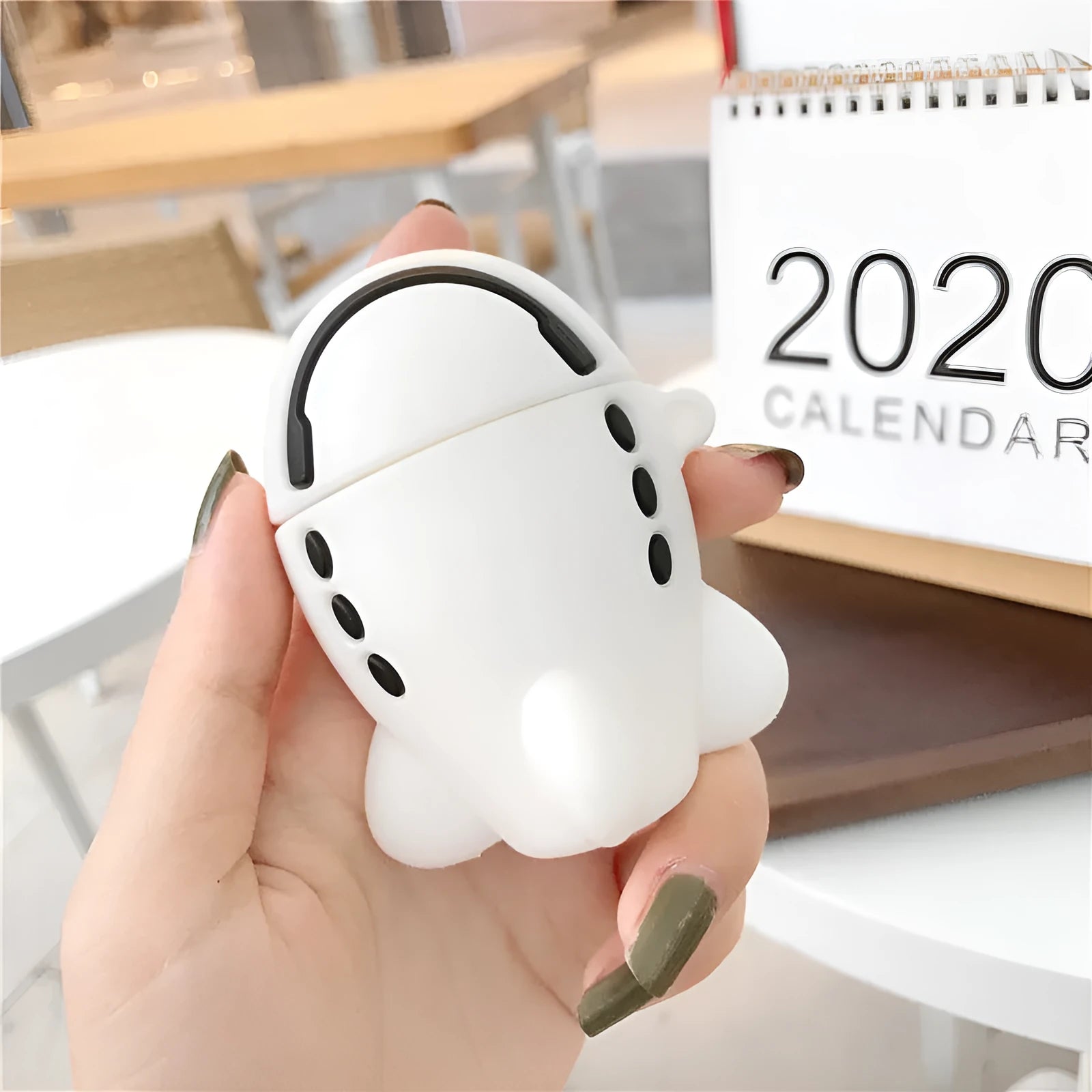 Silicone protective case for Apple AirPods with flip-top cover, cartoon aeroplane headset design, and detachable hook.