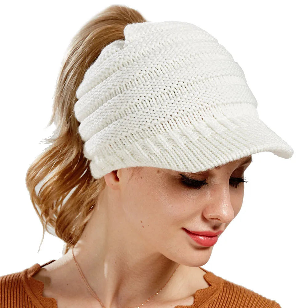 Woman wearing a thick knitted beanie with a ponytail threaded through the hole in the crown.