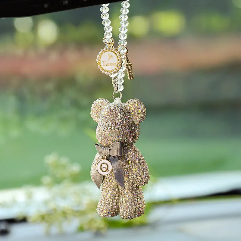 Close-up of a crystal rhinestone Violent Bear ornament on a car rearview mirror.