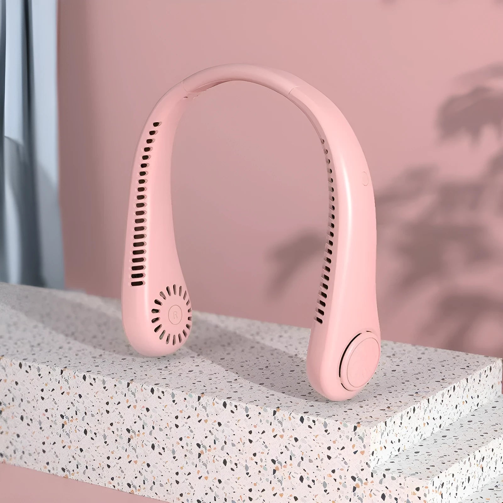 Pink USB rechargeable bladeless neck fan hanging with flexible neckband.