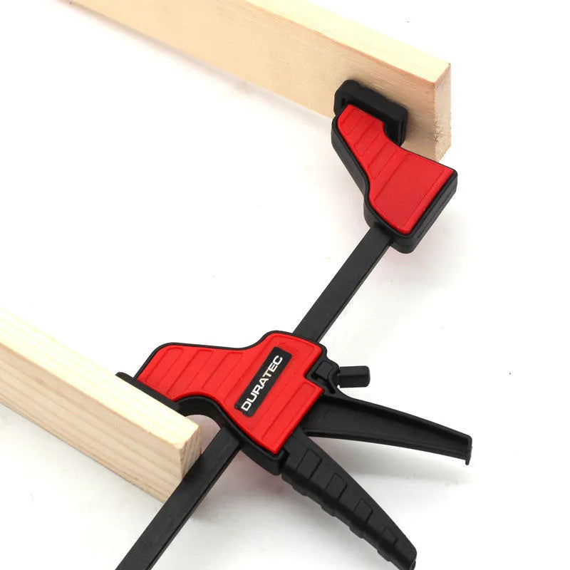 Black plastic woodworking clamp with quick-release lever and rubber grip pads in multiple sizes