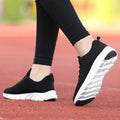 Women's running shoes in black, pink and white colours showing flyweave upper texture
