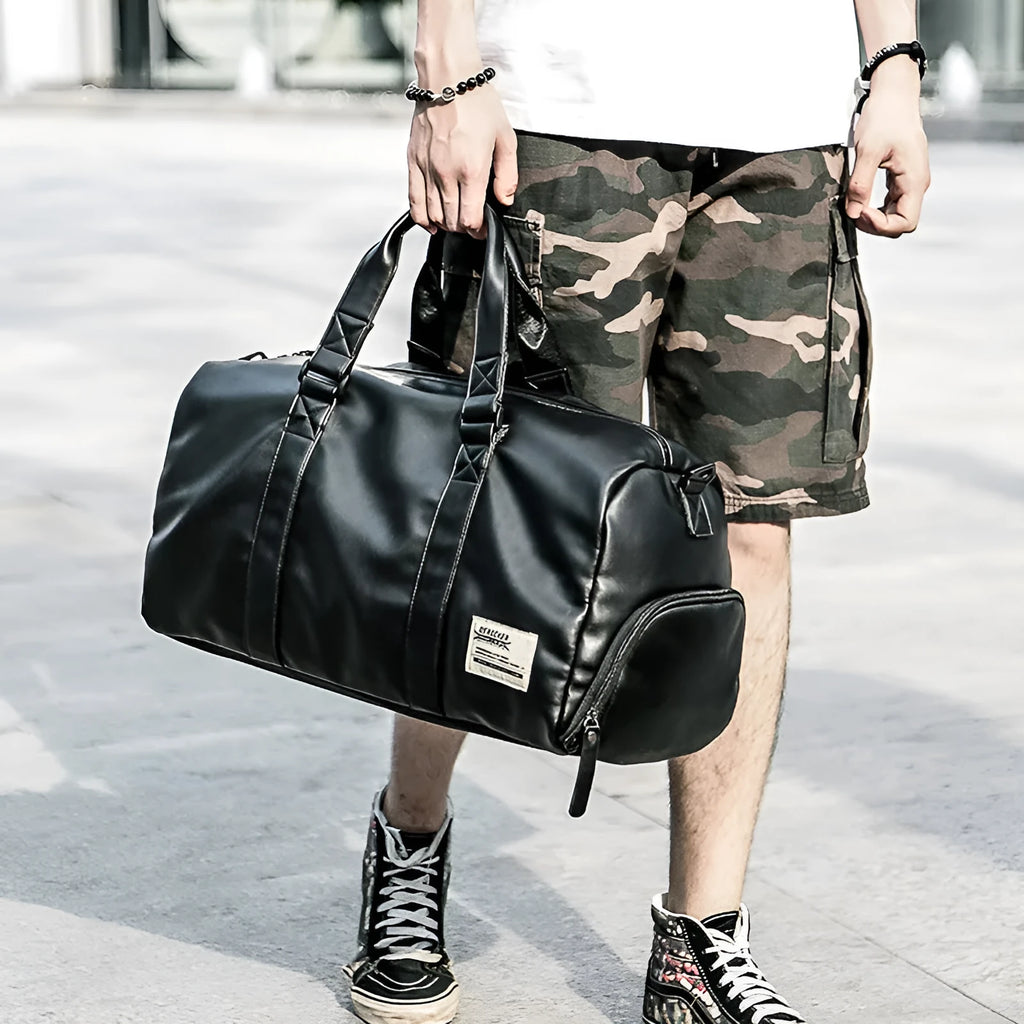 Large black PU leather sports training bag showing multiple zippered pockets and a single shoulder strap.