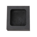 Square box-shaped graphite crucible for melting precious metals like gold and silver on a workshop table.
