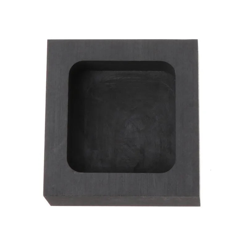 Square box-shaped graphite crucible for melting precious metals like gold and silver on a workshop table.