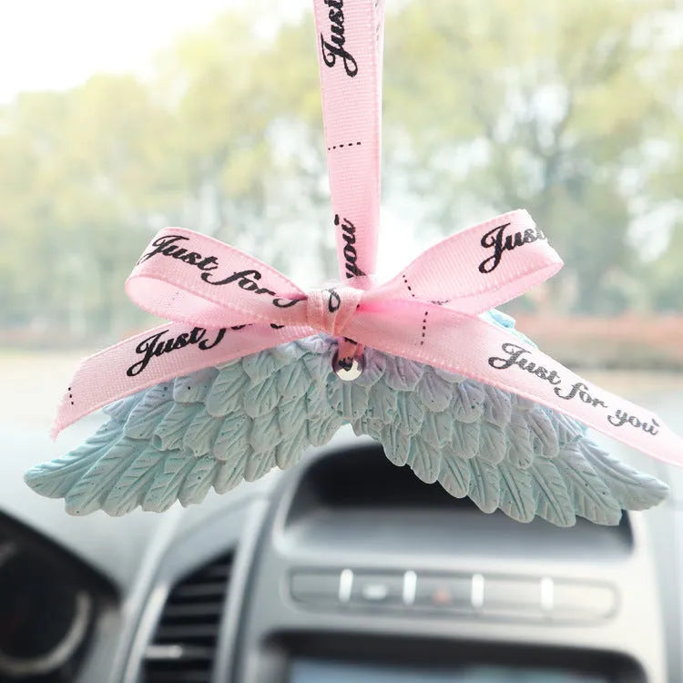 Angel wings gypsum car perfume pendant with black ribbon and white wings hanging from a rearview mirror