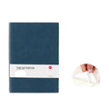 Simple solid colour thickened notebook in red, open on a desk with a pen.